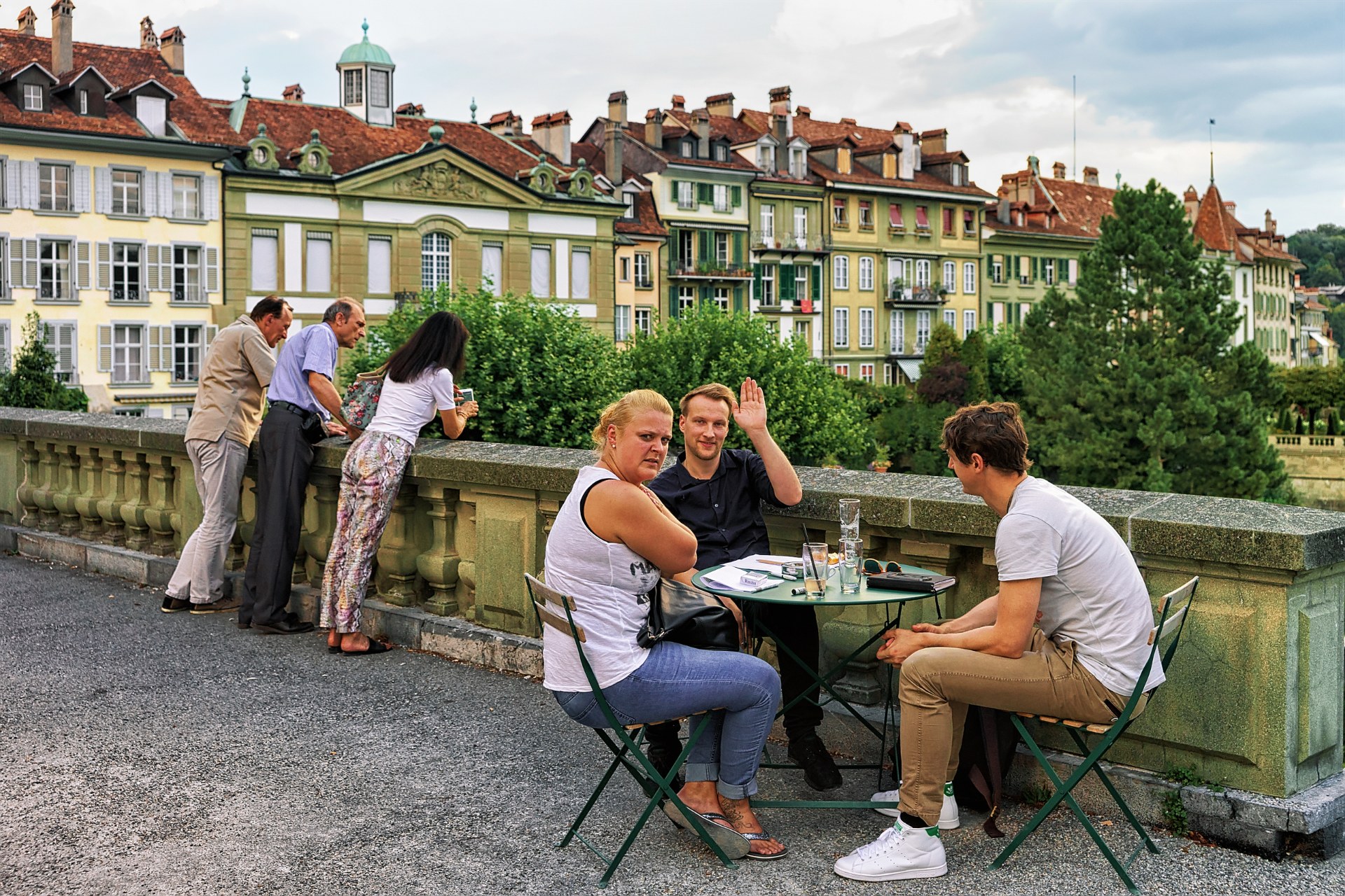 Freunde an einem Tisch eines Straßencafés auf der Münsterplattform in der Berner Altstadt